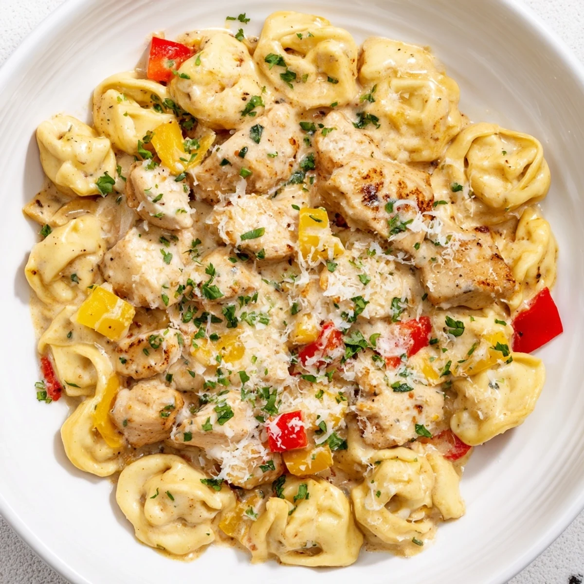 Steaming bowl of Zesty Cajun Garlic Parmesan Chicken Tortellini featuring creamy sauce, herbs, and tender chicken.