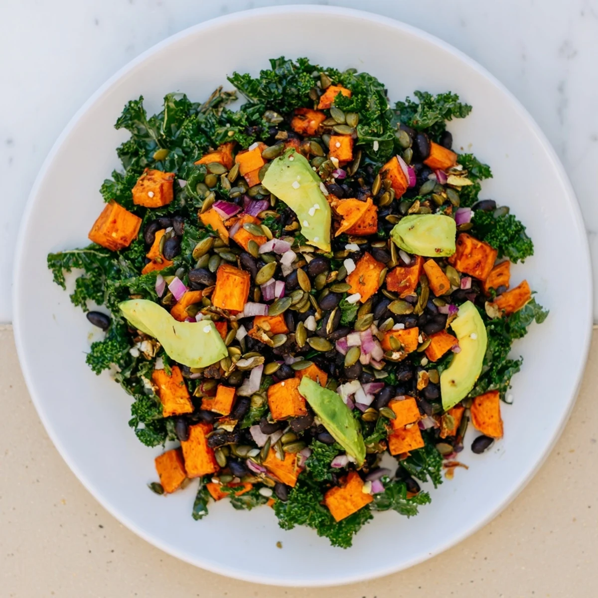 A colorful bowl of massaged kale salad showing perfectly cooked sweet potato and a flavorful lime dressing.