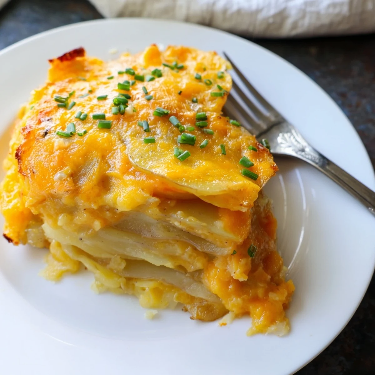 A casserole dish showing creamy, Southern-style cheesy scalloped potatoes, layered with rich cheddar.
