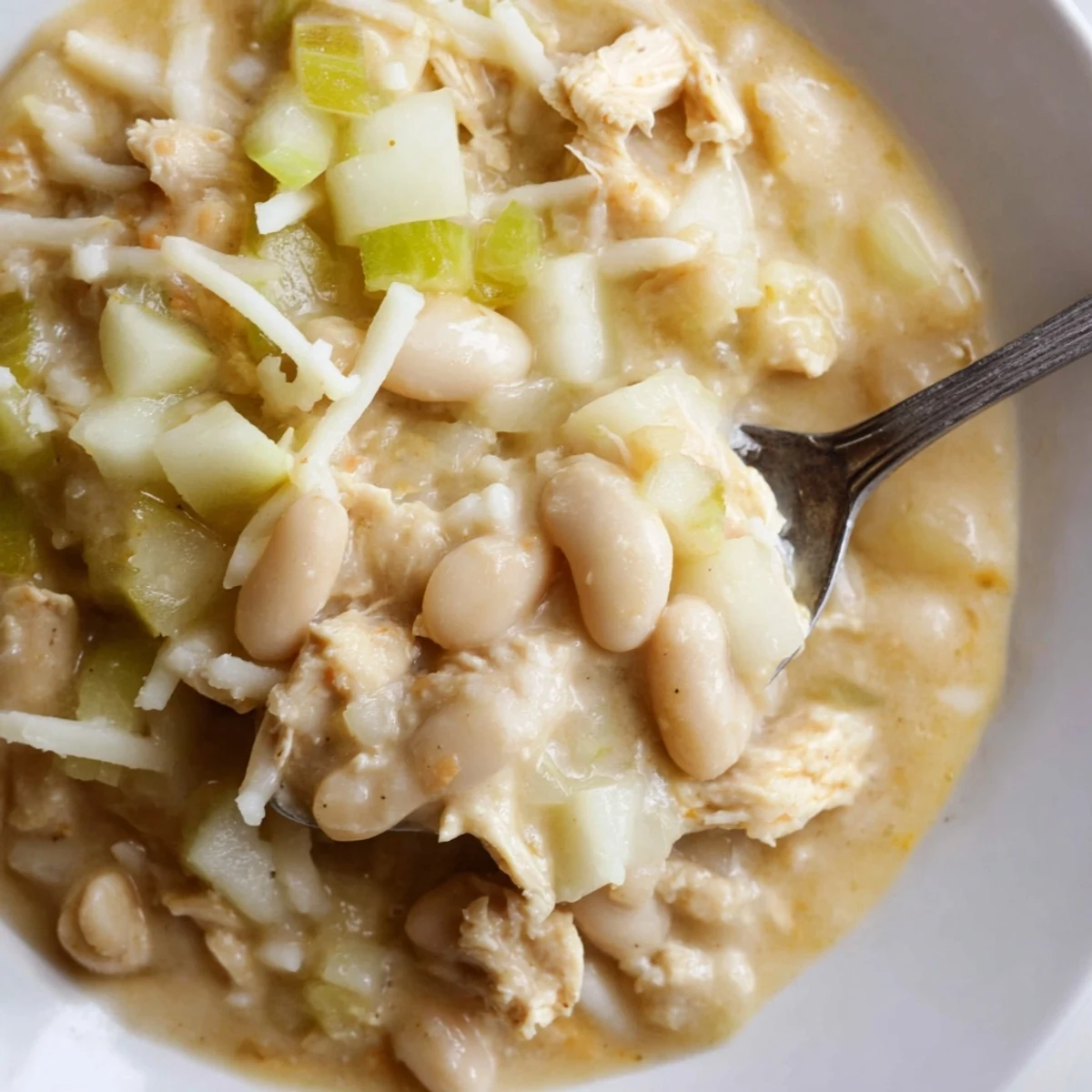 A steaming bowl of 35-Minute White Cheddar Apple Chicken Chili, topped with extra cheddar and apples.