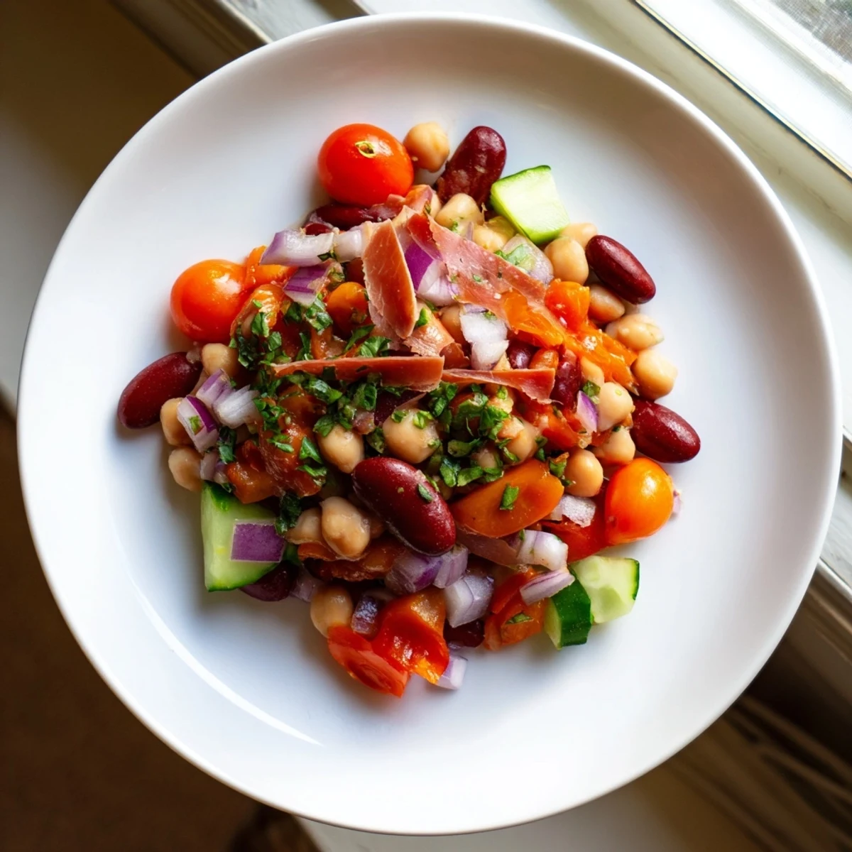 A refreshing close-up showcases the Italian-inspired Dense Bean Salad with Prosciutto, ready to serve and enjoy.