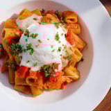 This oven-baked Shakshuka Pasta combines creamy runny eggs atop a vibrant tomato and pepper base.