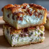 Clotted cream cookie bars with white chocolate chunks, rich and buttery, topped with a golden crust and soft, chewy texture.