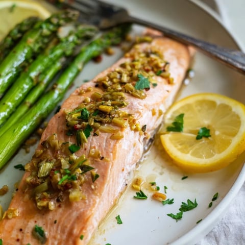 Succulent sheet pan lemon garlic salmon with asparagus, drizzled in zesty sauce.