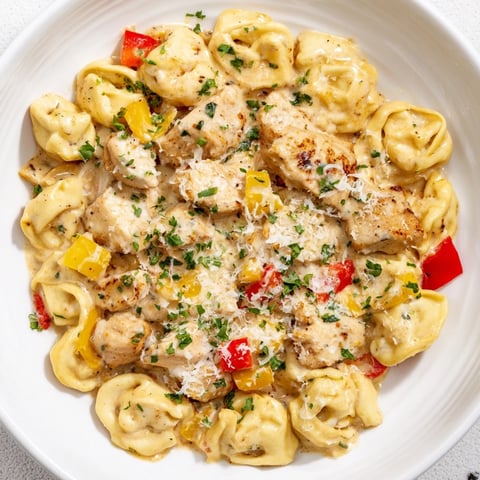 Steaming bowl of Zesty Cajun Garlic Parmesan Chicken Tortellini featuring creamy sauce, herbs, and tender chicken.