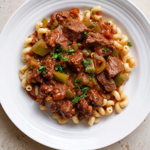 A steaming bowl of goulash with beef and tender pasta, ready for a comforting family dinner.