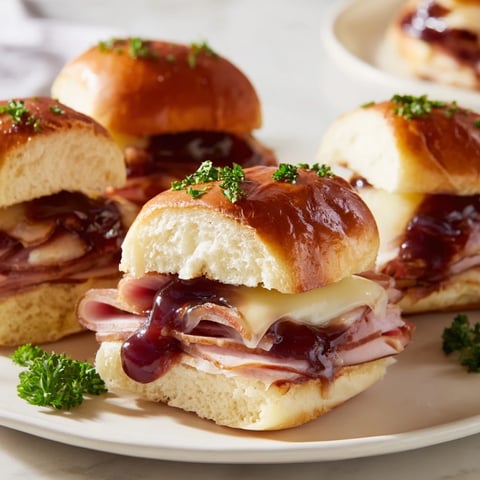 Golden, bubbly cherry-glazed ham and cheese slider mashup with melty cheese, perfect for sharing.