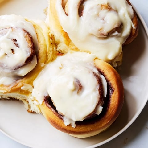 Fluffy Viral TikTok Heavy Cream Cinnamon Rolls baking in the oven, with golden-brown tops and drizzled cream.