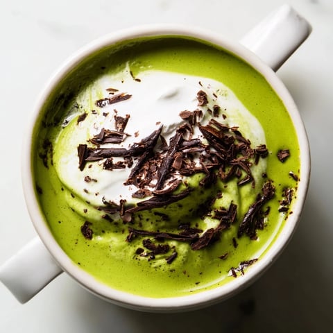 Steaming Collagen Peppermint Mocha Matcha Latte, a vibrant green and cocoa-brown drink topped with whipped cream.