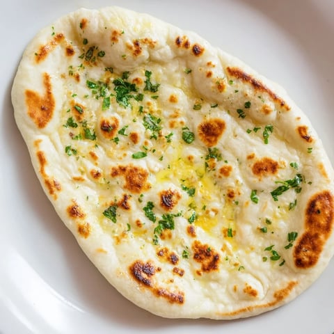 Golden-brown Homemade Garlic Naan Bread, hot off the skillet, brushed with garlic-infused butter.