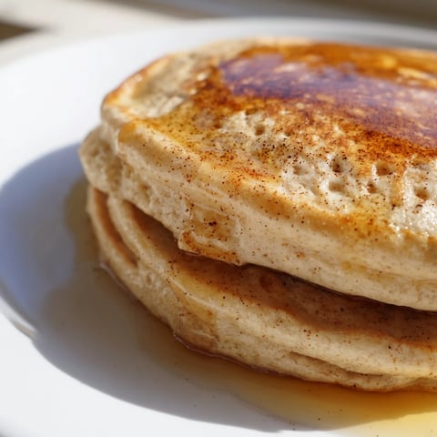 Golden, fluffy Protein Banana Pancakes, ready to stack with fresh berries & drizzled with syrup.