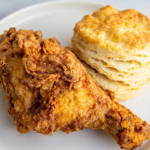 Crispy skin on Southern Fried Chicken, a warm plate with flaky buttermilk biscuits, ready to be enjoyed.