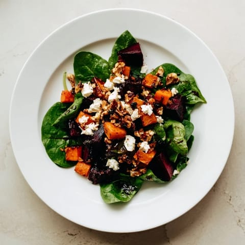 Golden roasted butternut squash and beets in a fresh spinach salad with tangy dressing and goat cheese.