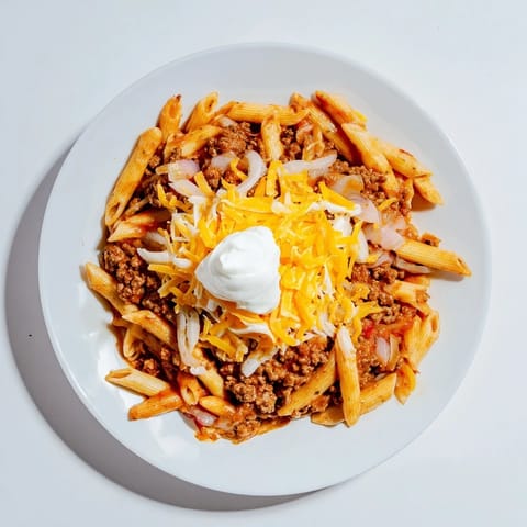 A sizzling skillet of Easy Beef Enchilada Pasta, topped with melted cheddar cheese ready to eat.