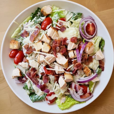 This fresh Costco Chicken Bake Salad Bowl presents a vibrant mix of ingredients and a creamy Caesar dressing in a bowl.