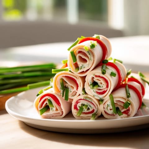 Folded turkey roll-ups with cream cheese filling, garnished with fresh chives, ready to serve and enjoy.
