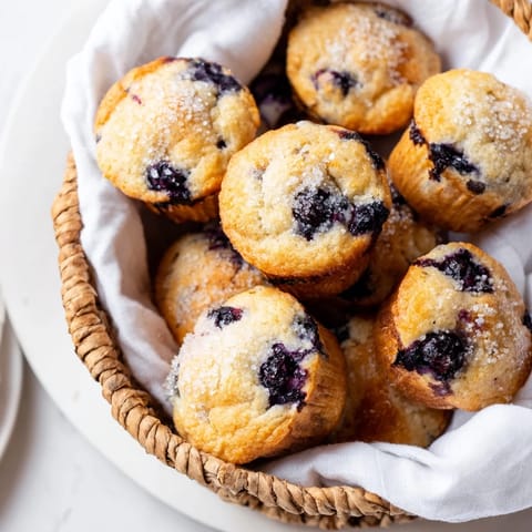 Golden-brown mini blueberry muffins, perfect for brunch, nestled in a woven basket.