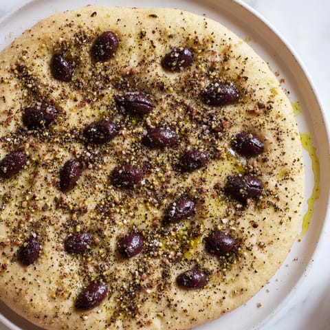 Freshly baked Zaatar Olive Focaccia, fragrant with zaatar and oil, studded with Kalamata olives.