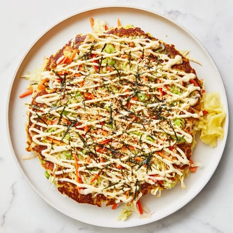 Savory Japanese Okonomiyaki Pancakes served hot, garnished with vibrant green onions and pickled ginger on a cozy kitchen plate.