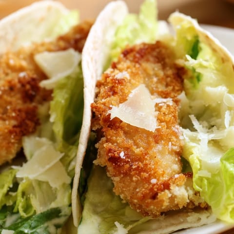 Savory Crispy Chicken Caesar Pita, freshly air-fried, stuffed with crunchy lettuce, shaved Parmesan, and drizzled with extra dressing.