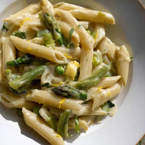Garlic Parmesan Spring Vegetable Pasta served in a warm bowl, garnished with fresh basil and extra Parmesan, ideal for spring dinners.  