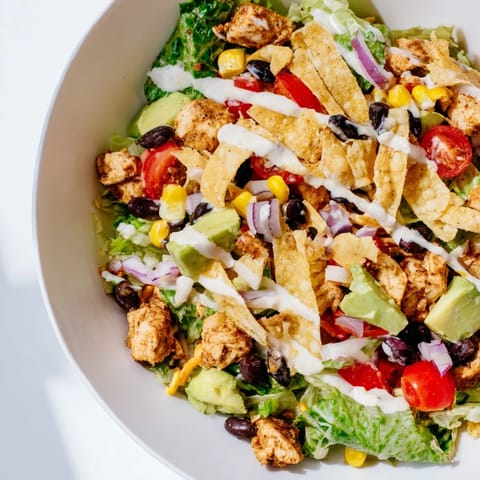 Chopped Chicken Taco Chopped Salad with diced avocado, cherry tomatoes, and cheddar cheese, drizzled with creamy salsa ranch dressing.