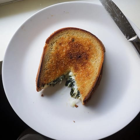 Sizzling Artichoke Spinach Grilled Cheese sandwich served warm with a bowl of tomato soup.