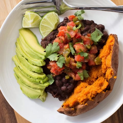 A close-up of roasted sweet potatoes with seasoned black beans and vibrant tomato salsa, perfect for a vegetarian, gluten-free dinner.  