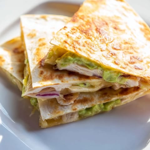 Grilled chicken and gooey melted cheese spill out of a toasted tortilla slice.
