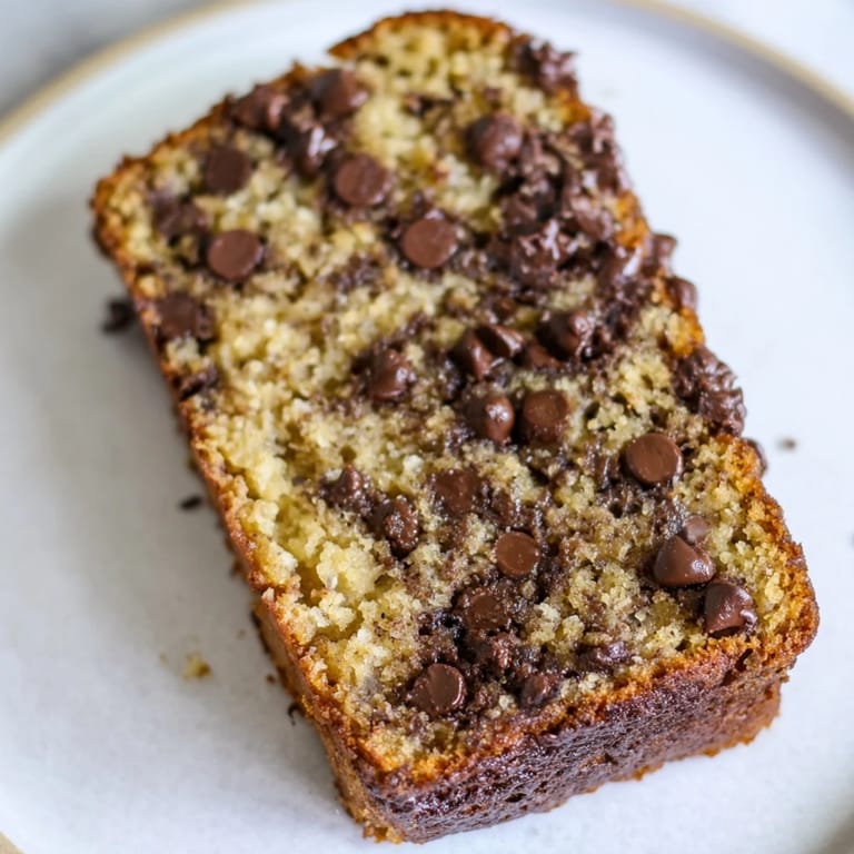 Sliced chocolate chip banana bread with gooey chocolate chunks, ideal for breakfast treat.