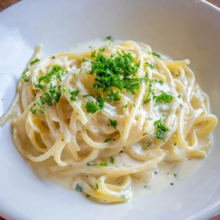 A heaping plate of delicious Creamy Three-Cheese Spaghetti, creamy and golden, with fresh parsley garnish.