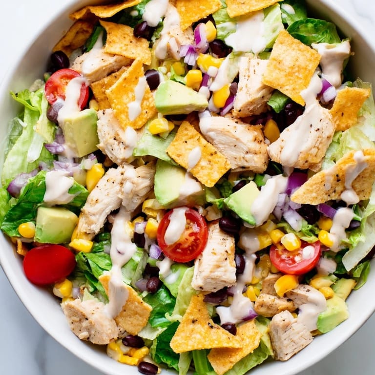 Freshly prepared Chicken Taco Chopped Salad featuring juicy taco-seasoned chicken, sweet corn, red onion, and a zesty lime ranch drizzle.