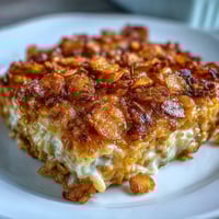 Funeral potatoes with crispy cornflake and cheddar crust in a golden baked casserole dish, creamy and cheesy with a crunchy topping.